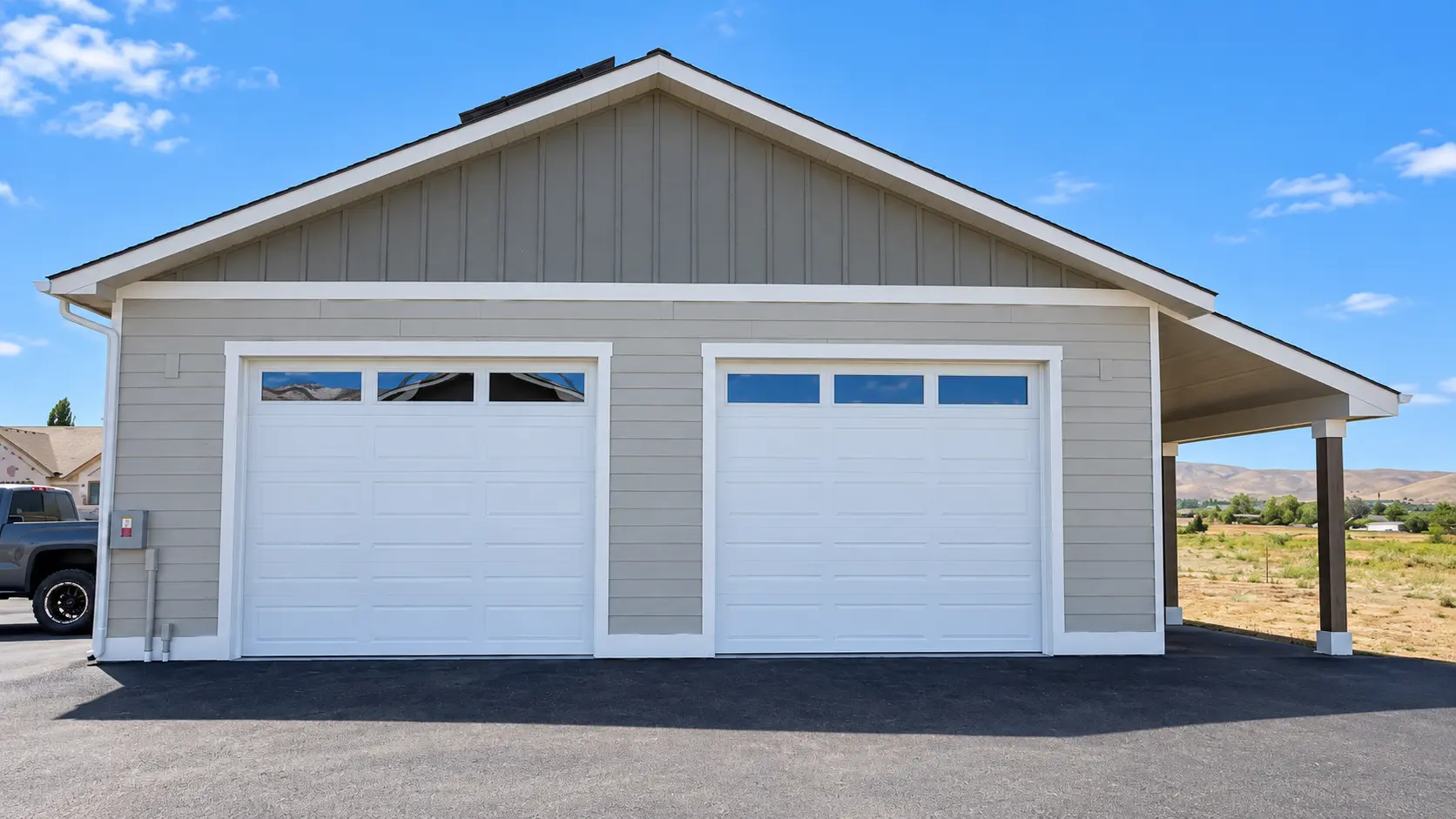 Two white garage doors with windows installed on a Central Washington outbuilding